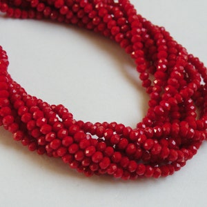 Peut inclure: Un brin de perles de verre facettées rouges. Les perles sont petites et ont une finition brillante.