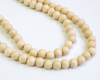 May include: A strand of natural wood beads, with a creamy white color. The beads are round and smooth, and they are strung together on a thin cord.
