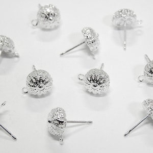 May include: Ten silver earring posts with a textured, round, sea urchin-like design. The posts are silver and have a loop at the top.