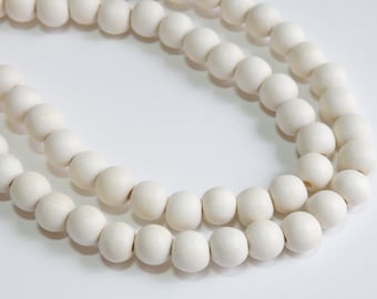 May include: A strand of white wooden beads, strung together in a circular shape.