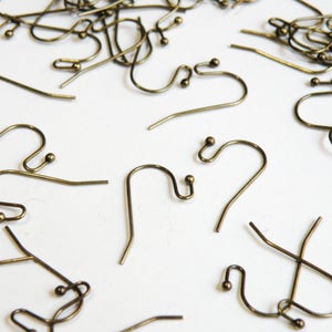 May include: A large quantity of gold-toned earring hooks. The hooks are made of metal and have a small ball at the end.