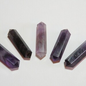 May include: Five amethyst crystal points arranged in a fan shape, with a purple and black colour gradient. The points are smooth and polished.