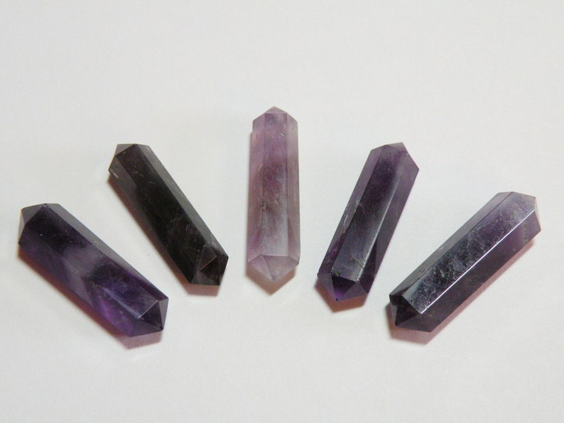 May include: Five amethyst crystal points arranged in a fan shape, with a purple and black colour gradient. The points are smooth and polished.