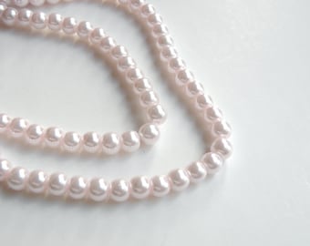 May include: A double strand of faux pearl beads in a pale pink color.