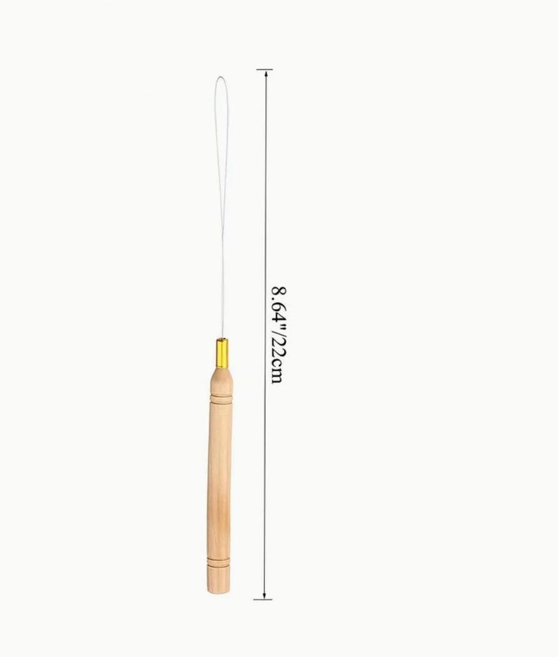 May include: A wooden hair extension tool with a gold-colored metal tip and a white string. The tool is 8.64 inches (22 cm) long. The wooden handle has a natural wood grain finish.