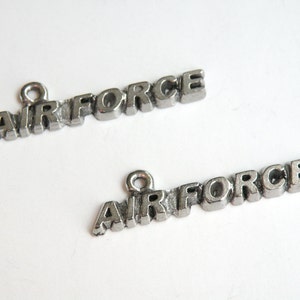 May include: Two silver charms with the word "AIR FORCE" spelled out in individual letters.