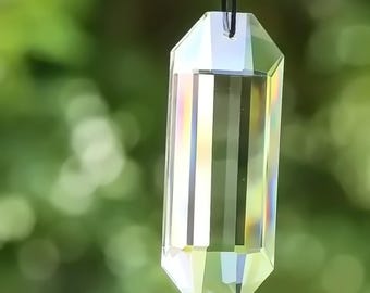 May include: A clear crystal prism pendant with a faceted design, hanging from a black cord. The prism reflects light, creating rainbow colors.
