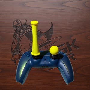 May include: A dark blue gaming controller featuring a tall, cylindrical yellow extension on the left analog stick and a spherical yellow topper on the right analog stick. The controller has standard directional buttons and a central PlayStation logo.