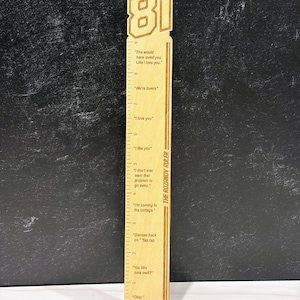 May include: A wooden ruler with the number 81 at the top. The ruler has etched measurements and phrases like "We're lovers" and "I love you." The text "THE ROZANOV RULER" is printed vertically on the side. The ruler is approximately 12 inches long.