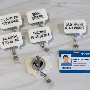 May include: Five white speech bubble badge reels with black text. Phrases include: IT'S SCARY, BUT YOU'RE BRAVE, WOW... GENETIC, YOU DESERVE SUNSHINE TOO, I'M COMING TO THE COTTAGE, and EVERYTHING WE DO IS A BAD IDEA. One reel is attached to a blue hospital ID card.