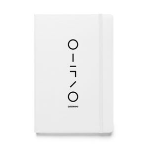 Puede incluir: Un cuaderno blanco con un diseño geométrico negro y la palabra "QUEERKIND" impresa en la parte inferior. El cuaderno tiene un cierre de banda elástica a juego. El diseño consta de líneas y círculos.