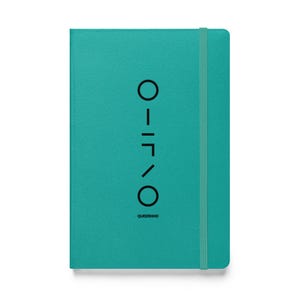 May include: Teal notebook with an elastic band closure. The cover displays a vertical design and the word "QUEERKIND" at the bottom. The notebook is rectangular and has a clean, minimalist design. The elastic band is teal.