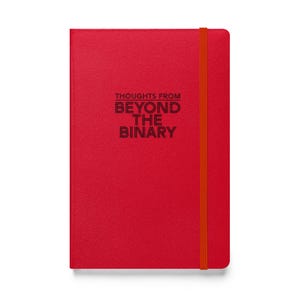 May include: A red notebook featuring the text "THOUGHTS FROM BEYOND THE BINARY" in black. It includes an orange elastic band closure.