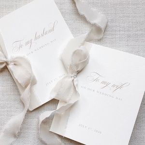Puede incluir: Dos tarjetas blancas atadas con una cinta blanca. Las tarjetas tienen el texto "To my husband on our wedding day" y "To my wife on our wedding day" con la fecha "July 17, 2020" impresa en cada tarjeta.