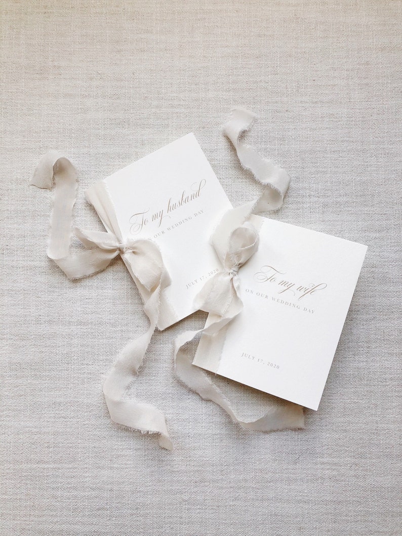 Puede incluir: Dos tarjetas blancas atadas con una cinta blanca. Las tarjetas tienen el texto "To my husband on our wedding day" y "To my wife on our wedding day" con la fecha "July 17, 2020" impresa en cada tarjeta.