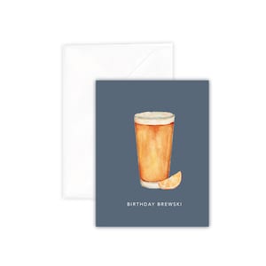 Puede incluir: Una tarjeta azul con una ilustración de acuarela de un vaso de cerveza y una rodaja de naranja. El texto "Birthday Brewski" está impreso debajo de la ilustración.