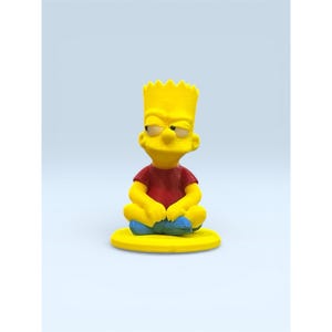 May include: A yellow figurine of Bart Simpson in a seated position, wearing a red shirt and blue shoes. The figurine has a yellow head with spiky hair and is sitting on a yellow base. The background is a light blue.