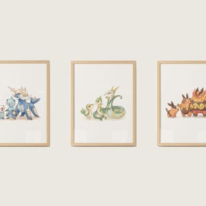 Peut inclure: Trois impressions encadrées à l'aquarelle représentant des créatures de dessins animés colorées. Les impressions sont dans des cadres en bois clair et sont exposées contre un mur neutre. L'œuvre représente divers personnages fantastiques dans un style fantaisiste.