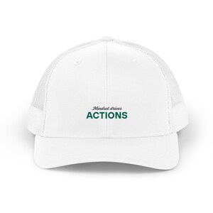 May include: White trucker hat with a mesh back and a curved brim. The hat features the text "Mindset drives ACTIONS" in green lettering across the front. The hat is designed for casual wear.