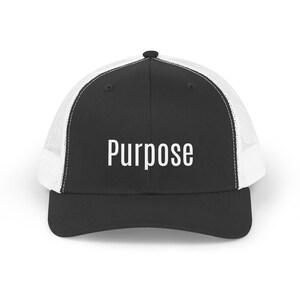 May include: Black and white trucker hat with the word "Purpose" in white block letters on the front. The hat has a black brim and front panel, with a white mesh back. The hat is a classic style, suitable for casual wear.