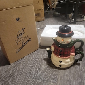 Puede incluir: Una taza de cerámica blanca con un asa negra y el texto "But first, coffee" en un estilo manuscrito. La taza está sobre una superficie blanca. La taza mide 10 cm de alto.