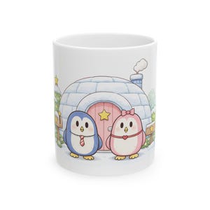 May include: White ceramic mug featuring a cartoon illustration of two penguins in front of an igloo. One penguin is blue with a tie, the other is pink with a bow. The igloo has a pink door with a star. Snow and trees are in the background.
