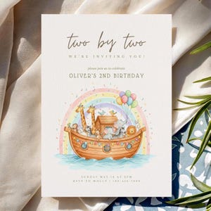 Może przedstawiać: Kremowe zaproszenie z tekstem "two by two" i "Oliver's 2nd Birthday". Zaproszenie zawiera akwarelową ilustrację Arki Noego ze zwierzętami, tęczą i balonami. Data i godzina również są uwzględnione.