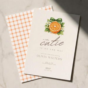 Könnte beinhalten: Babyparty-Einladung mit einer Illustration einer Orangenscheibe, einer grünen Schleife und dem Text "a little cutie is on the way". Die Einladung enthält Details für Olivias Babyparty, mit einem karierten Umschlag.