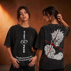 Puede incluir: Una camiseta gris carbón con efecto lavado al ácido que presenta un gráfico frontal con un ojo blanco, kanji japonés y el texto "Throughout the heaven and earth, I alone am the honored one". La espalda muestra una gran ilustración anime.