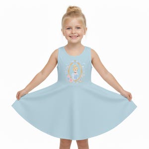 May include: A light blue sleeveless dress featuring a Cinderella graphic. The graphic is framed in gold with floral accents. The dress has a flared skirt and is designed for children.