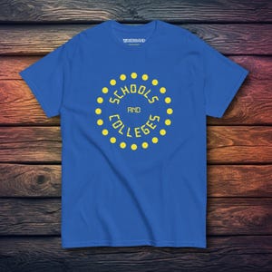May include: A bright blue short-sleeved t-shirt featuring a yellow graphic design in the centre. The design consists of a circle of yellow dots surrounding the yellow text "SCHOOLS AND COLLEGES". The brand name "WAXBRAND" is printed in white.