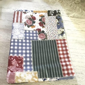 Könnte beinhalten: Ein Patchwork-Stoffartikel mit verschiedenen Mustern, darunter Blumenmuster, Vichy-Karo und Streifen. Die Farbpalette umfasst Rot, Blau, Weiß und Grün. Der Artikel ist ein kleines, rechteckiges Textil.