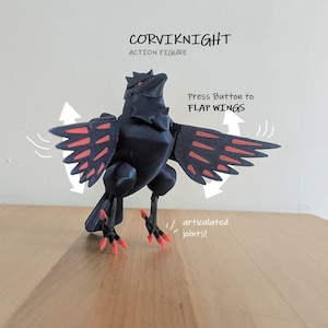 Könnte beinhalten: Eine schwarze Corviknight-Actionfigur mit roten Akzenten an Flügeln und Füßen. Die Figur enthält den Text CORVIKNIGHT ACTION FIGURE, Press Button to FLAP WINGS und articulated joints, wobei weiße Pfeile die Flügelbewegung anzeigen.
