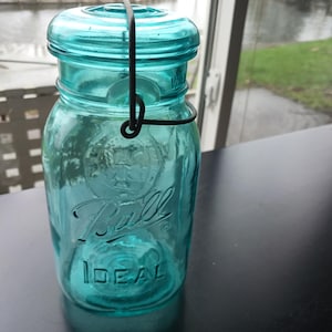 May include: A set of three ceramic mugs with a speckled, cream-colored glaze. Each mug features a different hand-painted floral design in shades of blue, green, and yellow. The mugs have a simple, rounded shape and a comfortable handle.