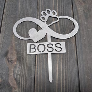 May include: A silver metal garden stake with an infinity symbol, heart, and paw print design. The word "BOSS" is cut out on a rectangular sign. The stake is designed for outdoor use.