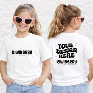 以下が含まれることがあります： 前面に「KIWIBERRY Mockups」、背面に「YOUR DESIGN HERE」と書かれた2枚の白いTシャツ。 ピンクのサングラスとブルージーンズを着用した人がシャツを着ています。