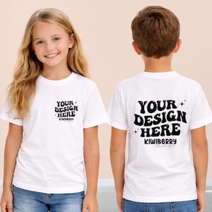 Pode incluir: Duas crianças vestindo camisetas brancas. A frente da camisa da menina tem o texto "YOUR DESIGN HERE" e "KIWIBERRY" em preto. A parte de trás da camisa do menino tem o mesmo texto. Ambas as camisas são de manga curta.