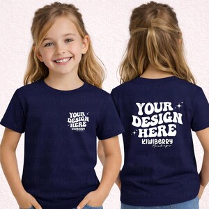 Puede incluir: Camiseta azul marino con texto blanco "YOUR DESIGN HERE" en la parte delantera y trasera. El texto frontal es más pequeño y en un diseño de bolsillo. El texto posterior es más grande y estilizado. La camiseta está en una persona joven.