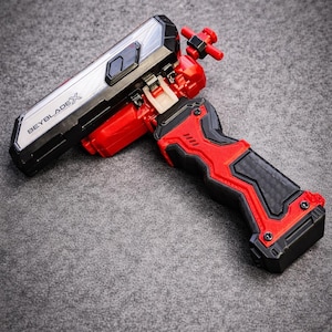 Puede incluir: Un lanzador Beyblade X rojo y negro con una secci&oacute;n superior plateada y negra. El lanzador tiene un agarre texturizado y el texto "BEYBLADEX" es visible en el lateral. El lanzador est&aacute; dise&ntilde;ado para lanzar peonzas Beyblade.