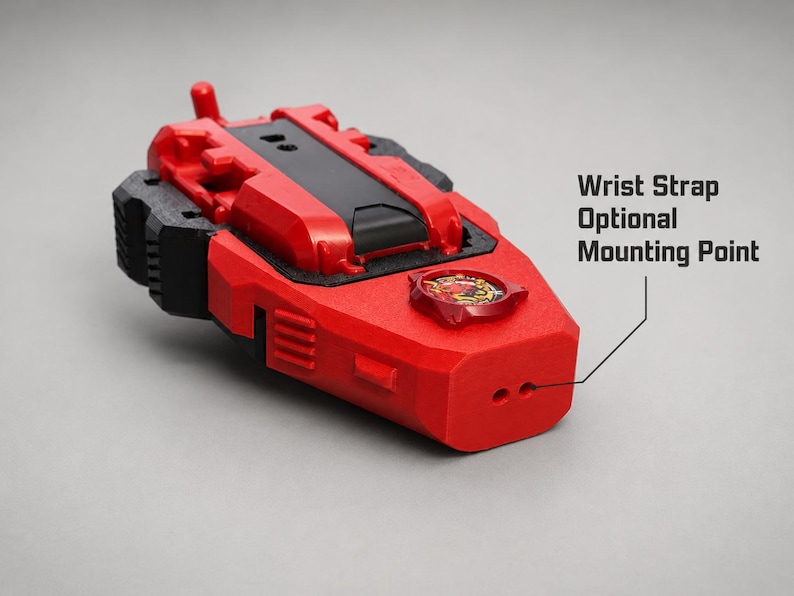 May include: A red and black plastic device featuring a central black panel, a circular emblem with a graphic design, and a front-facing section with two small holes labelled as a Wrist Strap Optional Mounting Point for attachment purposes.
