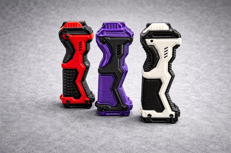 Puede incluir: Tres empu&ntilde;aduras futuristas en rojo, morado y blanco. Cada empu&ntilde;adura tiene un mango texturizado y un dise&ntilde;o geom&eacute;trico con detalles en negro. Las empu&ntilde;aduras est&aacute;n dise&ntilde;adas para un dispositivo y se muestran sobre una superficie gris.