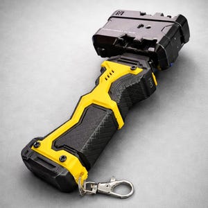 Puede incluir: Un dispositivo port&aacute;til negro y amarillo con un agarre texturizado y un cierre met&aacute;lico. El dispositivo tiene una secci&oacute;n superior rectangular y un dise&ntilde;o de acento amarillo. El dise&ntilde;o general es moderno e industrial.