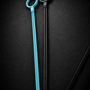 May include: Two cable ties, one light blue and one black, are displayed against a black background. Each tie has a circular head and a long, ridged body. The light blue tie is on the left, and the black tie is on the right.
