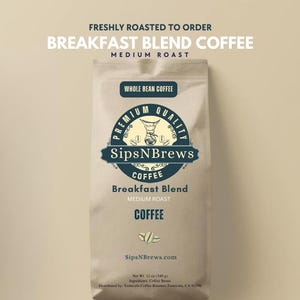 May include: A tan bag of whole bean coffee with the text "Breakfast Blend Coffee" and "SipsNBrews" in navy blue. The bag also includes the text "Medium Roast" and "Whole Bean Coffee". The bag weighs 12 oz (340 g).