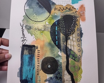 Puede incluir: Pintura abstracta en acuarela sobre papel con una mezcla de colores que incluyen azul, verde, dorado y negro. La obra de arte presenta formas geométricas, líneas y salpicaduras, creando un efecto texturizado y en capas. La pintura está sostenida por una mano.