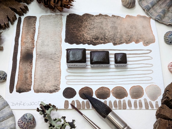 Darkwoods: handmade granulating brown-black watercolour paint with red undertone in half, quarter, and eighth pans. Vegan watercolor binder