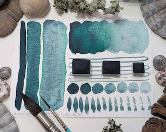 Green lagoon: a dark oceanic blue-green with black granulation. Handmade watercolour paint in 3 pan sizes, made with vegan watercolor binder