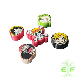 May include: A collection of colorful, cartoon character-themed accessories. The set includes various designs featuring faces and symbols, with a red, yellow, green, and black color scheme. The accessories are arranged on a white background.