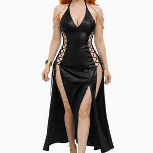 May include: A black halter dress with a plunging neckline and high slits. The dress features gold chain accents and lace-up detailing on the sides. The model is wearing gold sandals and a gold headband.