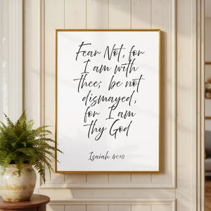 May include: A framed print with the text "Fear Not, for I am with thee; be not dismayed, for I am Thy God" and the reference "Isaiah 41:10" in elegant script. The frame is gold, and the print is displayed on a white background.